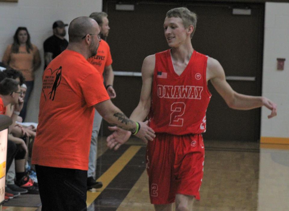 Onaway junior guard Jadin Mix (2) gets a handshake from head coach Eddy Szymoniak during the closing minutes of Tuesday's matchup at Pellston.