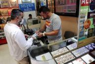 Gold dealer Gunay Gunes talks to a customer who wants to buy gold, in Istanbul