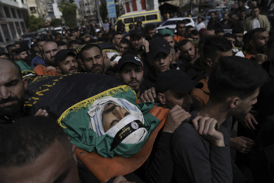 Mourners carry the bodies of three Palestinian militants, draped in the flag of the Islamic Jihad militant group, during their funeral in the West Bank city of Jenin, Thursday, March 9, 2023. Palestinian officials say at least three Palestinian militants were killed after Israeli security forces entered a village in the northern occupied West Bank. The Israeli Police said Thursday that troops carried out a raid in Jaba to apprehend suspects wanted for attacks on Israeli soldiers in the vicinity. The three militants killed included the head of a local Palestinian militant group. (AP Photo/Nasser Nasser)