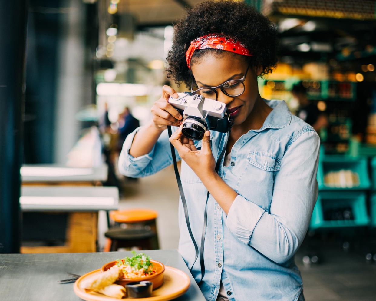 African American woman photographing her food on a cafe counter