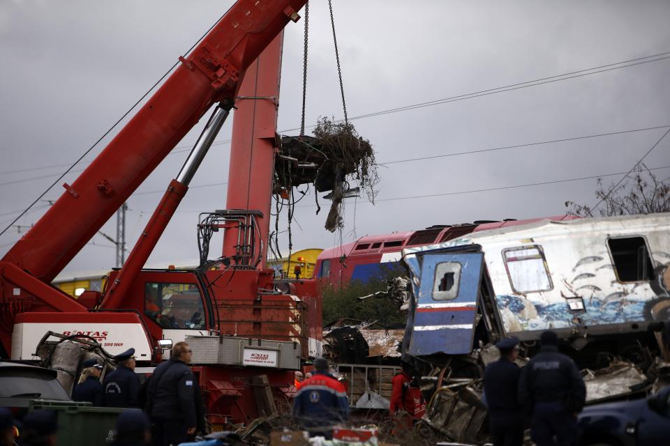 A crane removes debris of a train after a collision in Tempe, about 376 kilometres (235 miles) north of Athens, near Larissa city, Greece, Wednesday, March 1, 2023. Rescuers searched Wednesday through the burned-out wreckage of two trains that slammed into each other in northern Greece, killing and injured dozens of passengers. (AP Photo/Giannis Papanikos)