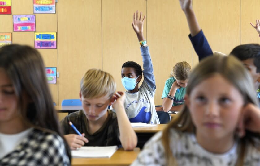 Redondo Beach, California-Hellelujah Borgic, age 11, raises his hand during his 5ht grade class at Tulita Elementary School while in teacher Wendy Demaria's class. Monday March 14 was the first day they are allowed to go maskless. At Tulita Elementary School in Redondo Beach, California students were given the option to attend with or without wearing a masks on March 14, 2022, the first day that that students across Los Angeles County have the option to remove their masks in class. L.A. Unified School District is an exception and students are still required to wear masks. (Carolyn Cole / Los Angeles Times)