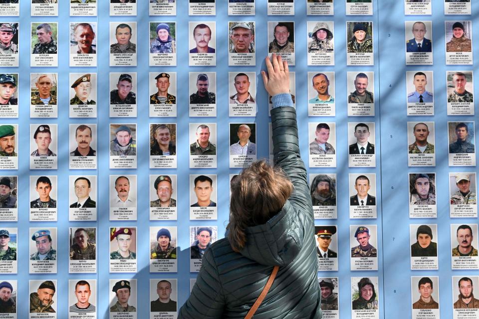 A woman touches a picture of her dead son at Memory Wall of Fallen defenders of Ukraine in the Russian-Ukrainian War during a ceremony marking the Day of Volunteer in Kyiv on March 14, 2023.