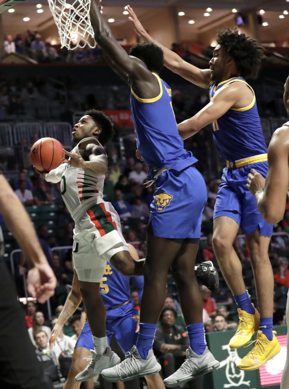 Miami guard Chris Lykes, left, goes to the basket as Pittsburgh forward Eric Hamilton, center, and guard Justin Champagnie, right, defend during the second half of an NCAA college basketball game, Sunday, Jan. 12, 2020, in Coral Gables, Fla. Miami won 66-58. (AP Photo/Lynne Sladky)