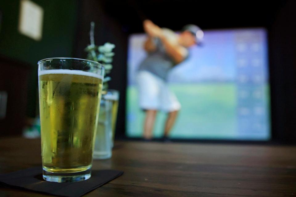 Beer sits on a table as Dane Kempf golfs at the newly opened Fore Score Golf Tavern on historic San Marco Square in Jacksonville.
