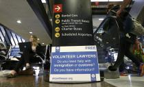 Asti Gallina, left, a volunteer law student from the University of Washington, sits at a station near where passengers arrive on international flights at Seattle-Tacoma International Airport Tuesday, Feb. 28, 2017, in Seattle. Gallina was volunteering with the group Airport Lawyer, which also offers a secure website and mobile phone app that alerts volunteer lawyers to ensure travelers make it through customs without trouble. Airport officials and civil rights lawyers around the country are getting ready for President Donald Trump's new travel ban, which is expected to be released as soon as Wednesday. (AP Photo/Ted S. Warren)