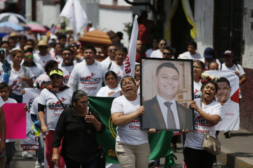 FILE - In this May 13, 2018 file photo, women carry a photo of the late Jose Remedios Aguirre, a mayoral candidate who was shot in broad daylight two days prior, during his funeral procession in Apaseo El Alto, Mexico. Remedios was the second mayoral candidate assassinated that week in the lead-up to general elections in July. (AP Photo/Eduardo Verdugo, File)