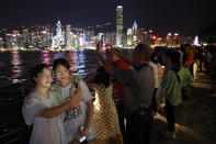 FILE - Chinese tourists take a selfie near the evening skyline of Hong Kong on Aug. 7, 2019. The exodus of tens of thousands of professionals from Hong Kong triggered by Beijing's crackdown on its civil liberties is being offset by new arrivals: mainland Chinese keen to move to the former British colony. (AP Photo/Vincent Thian, File)