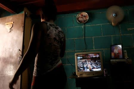 A woman walks past a TV showing the broadcast of the National Assembly session, in Havana, Cuba July 21, 2018. REUTERS/ Stringer