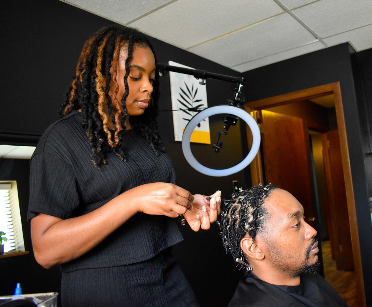 Tae Baylor, owner of the Loc Gallery in West Allis, styles client Tyce Batemon's hair into locs. Batemon, 32, just started growing his natural hair out in February, he said. Before, he didn't have the confidence to wear his natural hair, he said. "Now, I say to hell with that," Batemon said. "I'm going to be me, and I'm going to carry myself how I've been carrying myself."