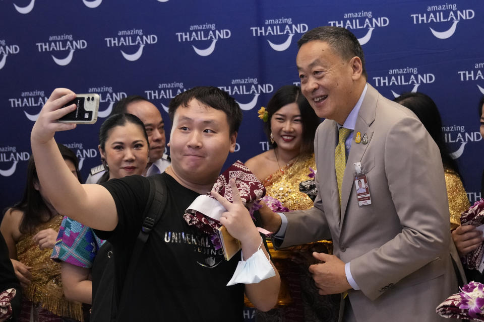 FILE - Chinese tourists takes selfies with Thailand's Prime Minister Srettha Thavisin, right, on their arrivals at Suvarnabhumi International Airport in Samut Prakarn province, Thailand, Monday, Sept. 25, 2023. Thailand and China will soon implement visa-free entry for each other’s citizens, Thai Prime Minister Srettha Thavisin said Tuesday, Jan. 2, 2024. (AP Photo/Sakchai Lalit, File)