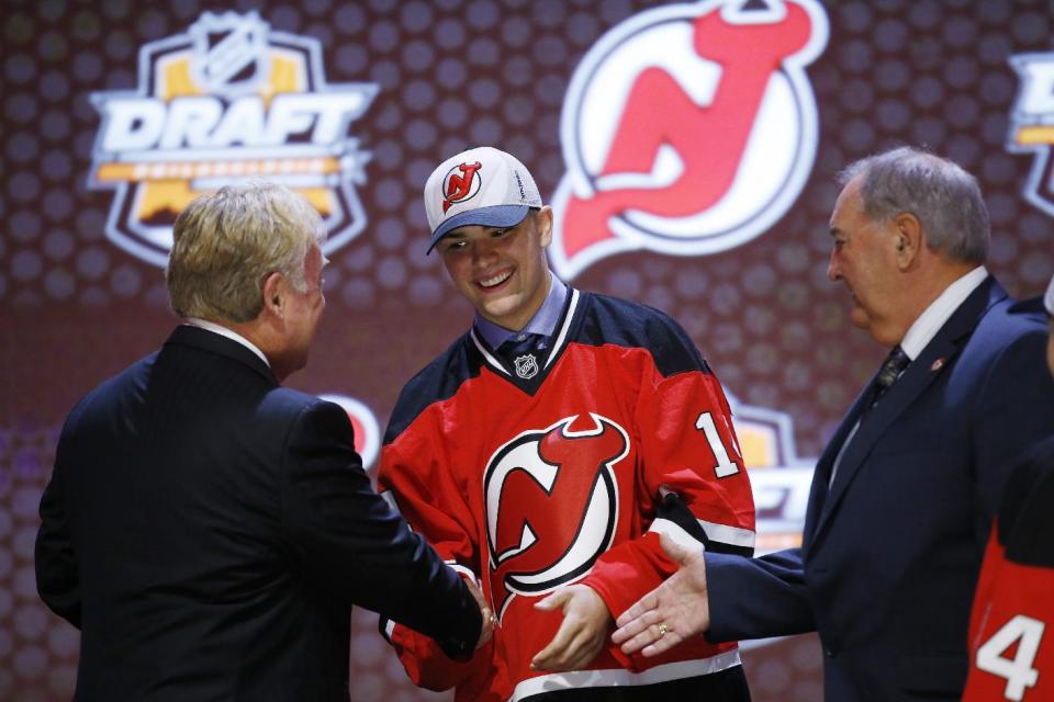 John Quenneville shakes hands with New Jersey Devils officials after being chosen 30th overall during the first round of the NHL hockey draft, Friday, June 27, 2014, in Philadelphia. (AP Photo/Matt Slocum)