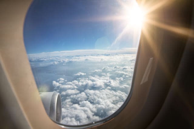 Looking outside of airplane window into bright sunlight beam