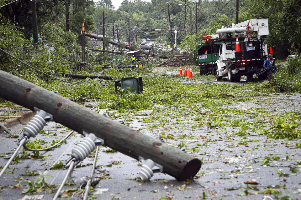 Utility crews work to remove broken poles and power lines. (Phil Sears / AP)