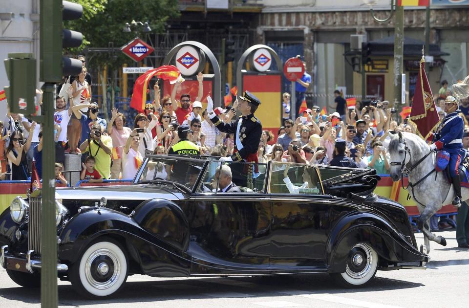 Spain's new King Felipe VI and his wife Queen Letizia wave to the crowd as they parade through the streets of Madrid from the Congress of Deputies to the Royal Palace in Madrid, June 19, 2014. (REUTERS/Victor Lerena/Pool)