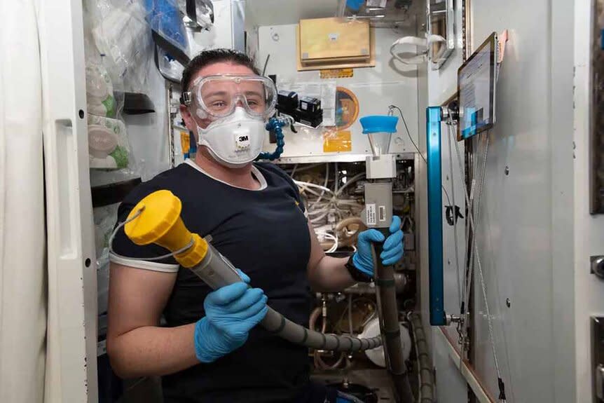 A NASA Astronaut plumbing holding a pipe.