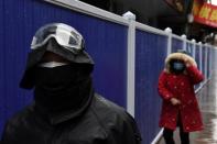 People wearing face masks walk next to barriers set up at a residential area in Wuhan