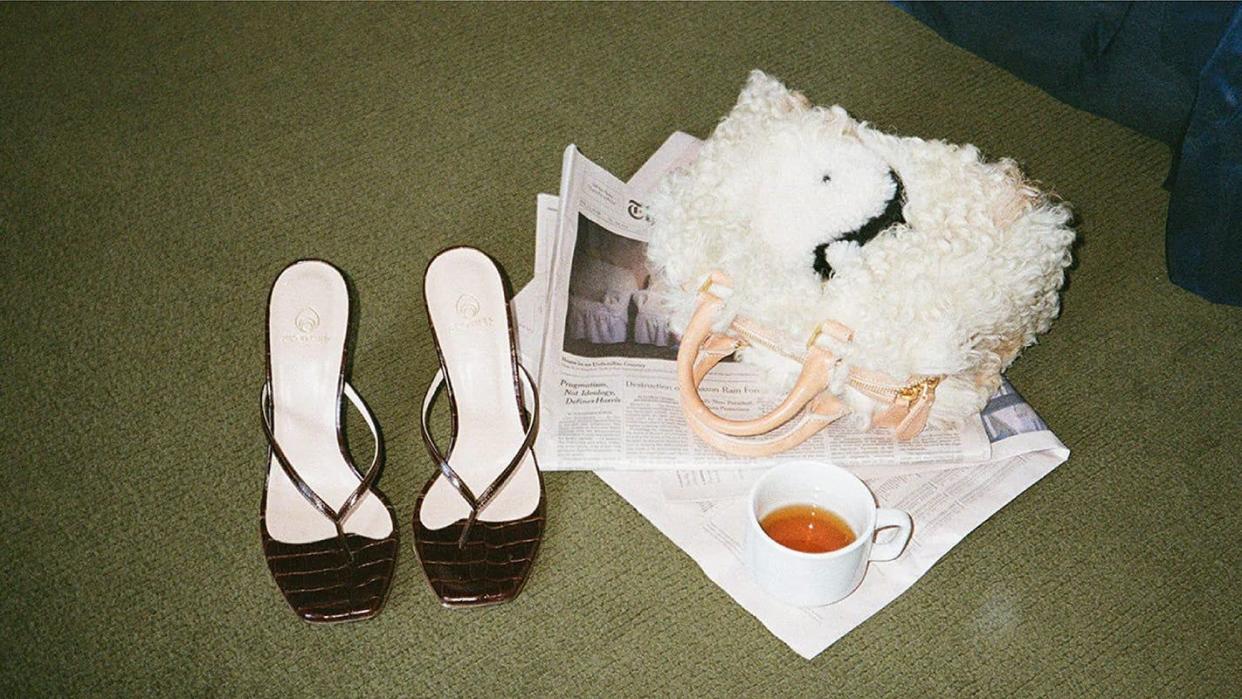 a brother vellies pair of heeled sandals next to a fuzzy bag and a teacup