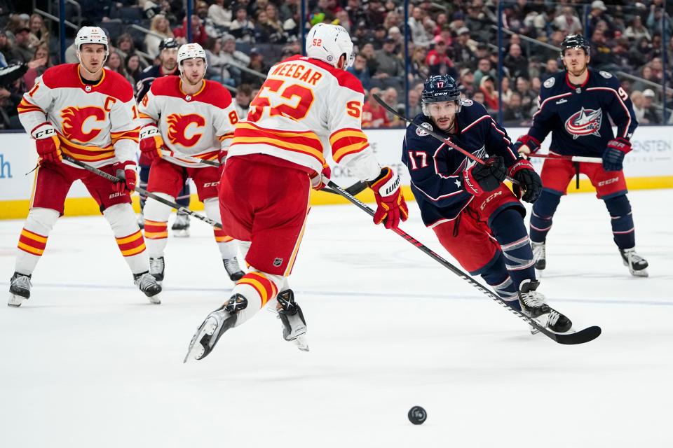 Oct 20, 2023; Columbus, Ohio, USA; Columbus Blue Jackets right wing Justin Danforth (17) dumps the puck past Calgary Flames defenseman MacKenzie Weegar (52) during the third period of the NHL hockey game at Nationwide Arena. The Blue Jackets on 3-1.