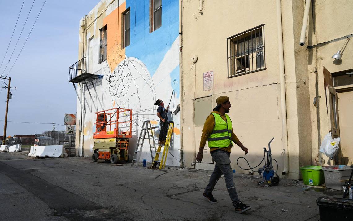 Fresno muralist Mauro Carrera, right, works with Rigo Garcia on a mural on a historical Chinatown building on China Alley in downtown Fresno on Thursday, Dec. 8, 2022. The project is in conjunction with the Fresno Arts Council and the California High-Speed Rail Authority.