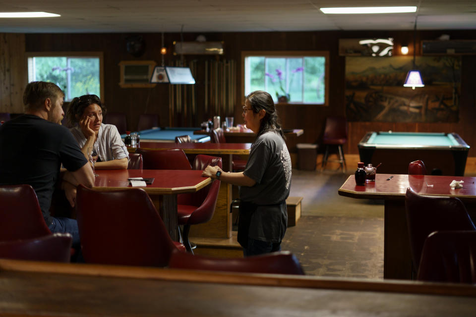 Yokie Johnson, right, co-owner of the restaurant, MontAsia, talks with customers Jacob and Laci Karp in Fishtail, Mont., Thursday, June 16, 2022. The main road into Fishtail was washed away by the recent floodwaters and Johnson worries the lack of traffic will hurt their business. (AP Photo/David Goldman)