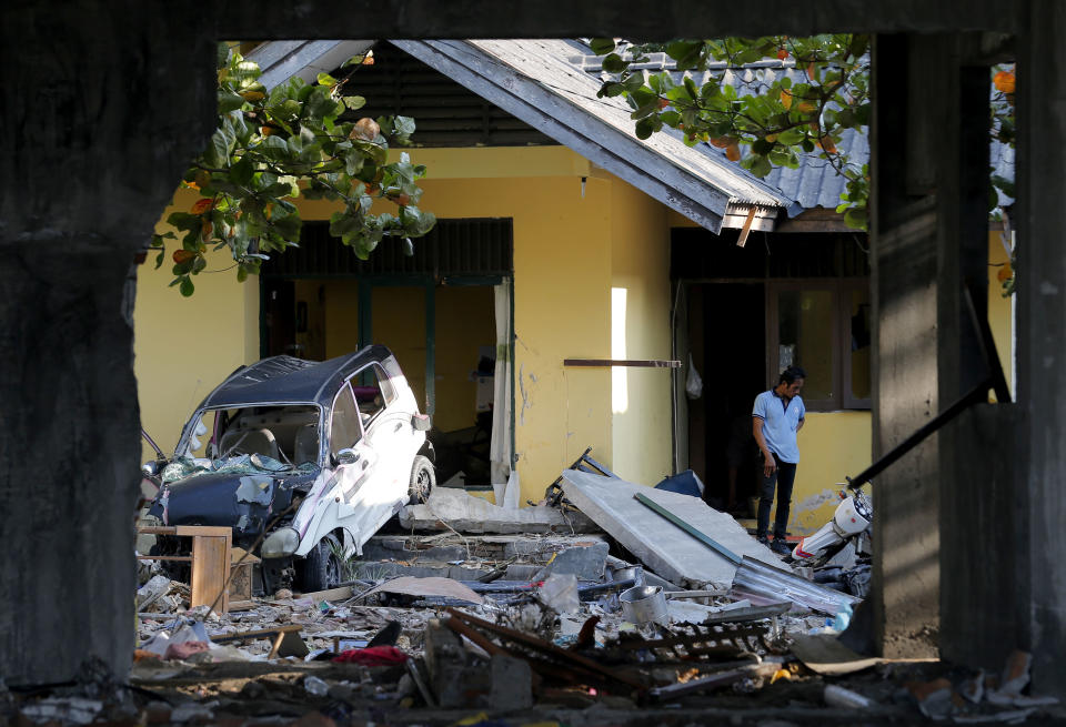 A man inspects his damaged home following a massive earthquake and tsunami at Talise beach in Palu, Central Sulawesi, Indonesia, Monday, Oct. 1, 2018. A mass burial of earthquake and tsunami victims was being prepared in a hard-hit city Monday as the need for heavy equipment to dig for survivors of the disaster that struck a central Indonesian island three days ago grows desperate. (AP Photo/Tatan Syuflana)