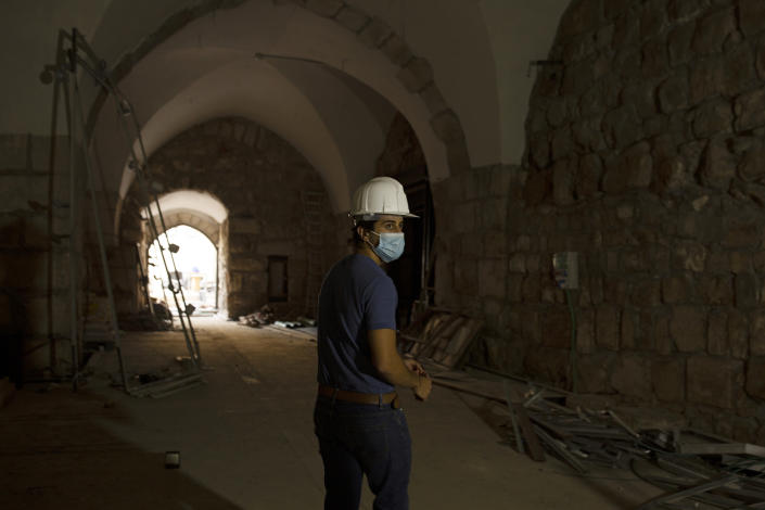 A staff member at the Tower of David Museum gives a tour to journalists in the Old City of Jerusalem, Wednesday, Oct. 28, 2020. The ancient citadel is devoid of tourists due to the pandemic and undergoing a massive restoration and conservation project. (AP Photo/Maya Alleruzzo)