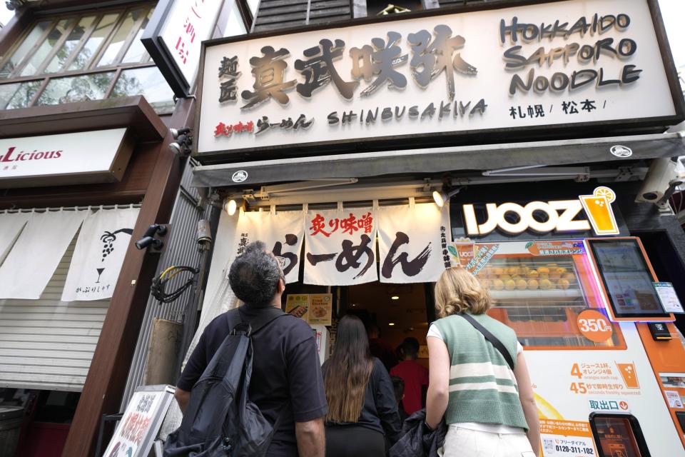 Participants of Tokyo Ramen Tours enter Shinbusakiya, a ramen shop which offers "Hokkaido classics," at Shibuya district on April 2, 2024, in Tokyo. (AP Photo/Eugene Hoshiko)