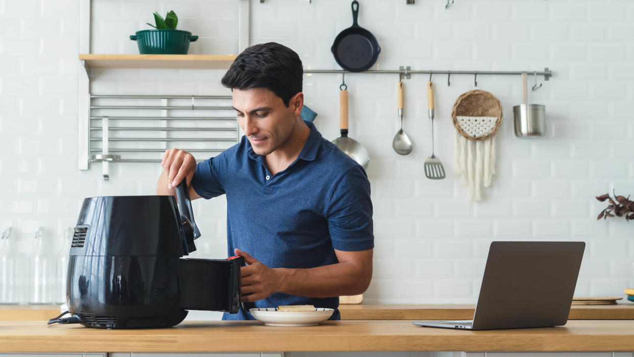  Man using an air fryer in kitchen. 