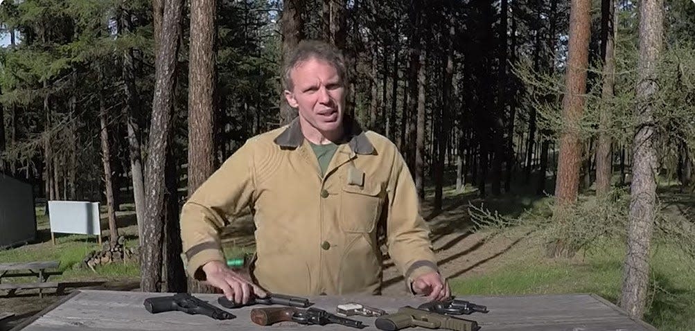 Paul Harrell standing in front of a table full of guns