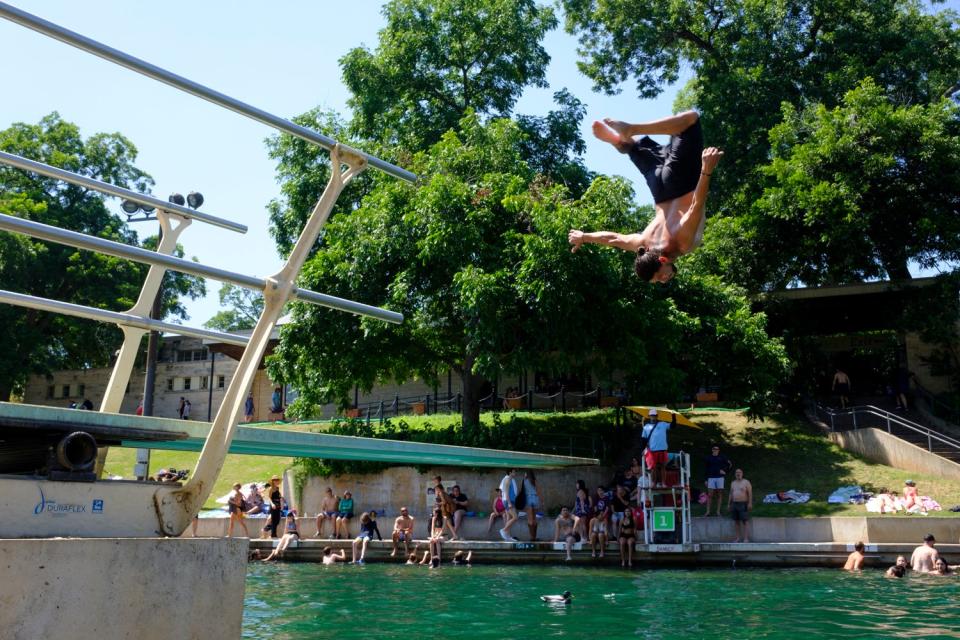 Un clavadista hace un salto mortal hacia atrás en la piscina Barton Springs.