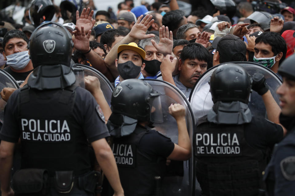 Police block soccer fans waiting to see Diego Maradona lying in state outside the presidential in Buenos Aires, Argentina, Thursday, Nov. 26, 2020. The Argentine soccer great who led his country to the 1986 World Cup title died Wednesday at the age of 60. (AP Photo/Natacha Pisarenko)