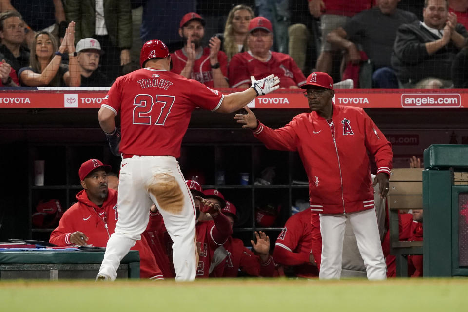 Los Angeles Angels' Mike Trout (27) celebrates with manager Ron Washington after scoring on a wild pitch by Philadelphia Phillies relief pitcher Seranthony Dominguez and throwing error by catcher Garrett Stubbs during the seventh inning of a baseball game, Monday, April 29, 2024, in Anaheim, Calif. Ehire Adrianza also scored. (AP Photo/Ryan Sun)