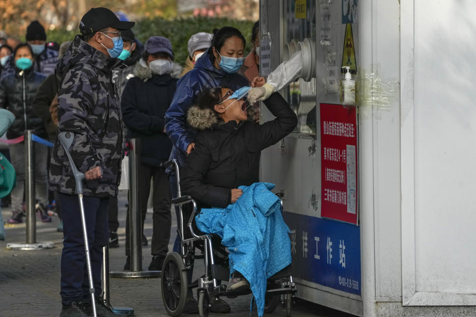 A woman on her wheelchair has her throat swabbed for a COVID-19 test at a coronavirus testing site in Beijing, Sunday, Nov. 27, 2022. Protests against China's overzealous zero-COVID policies in Shanghai continued on Saturday afternoon, after police cleared away hundreds of protesters in the early morning hours with force and pepper spray. (AP Photo/Andy Wong)