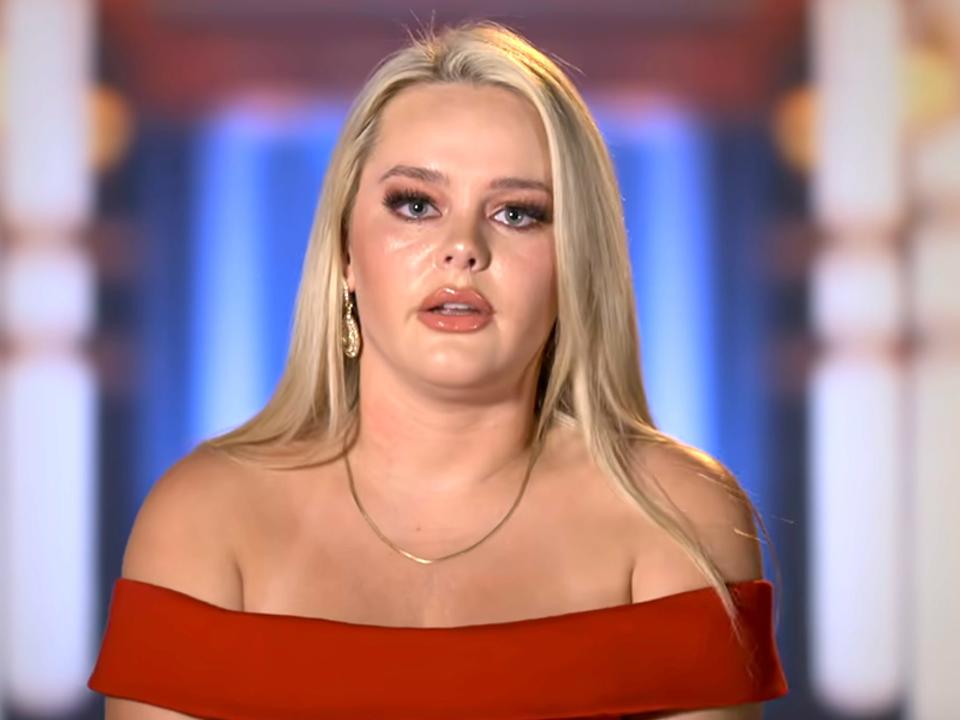 Taylor during a confessional interview on "Love Is Blind" season 5, wearing a red off-the-shoulder dress.