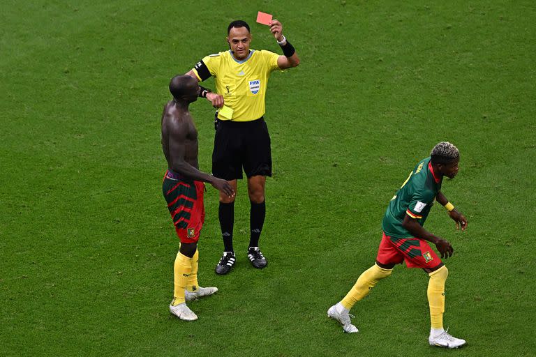 US referee Ismail Elfath shows a yellow card and then a red card to Cameroon's forward #10 Vincent Aboubakar after he took off his jersey to celebrate scoring his team's first goal during the Qatar 2022 World Cup Group G football match between Cameroon and Brazil at the Lusail Stadium in Lusail, north of Doha on December 2, 2022. (Photo by Anne-Christine POUJOULAT / AFP)