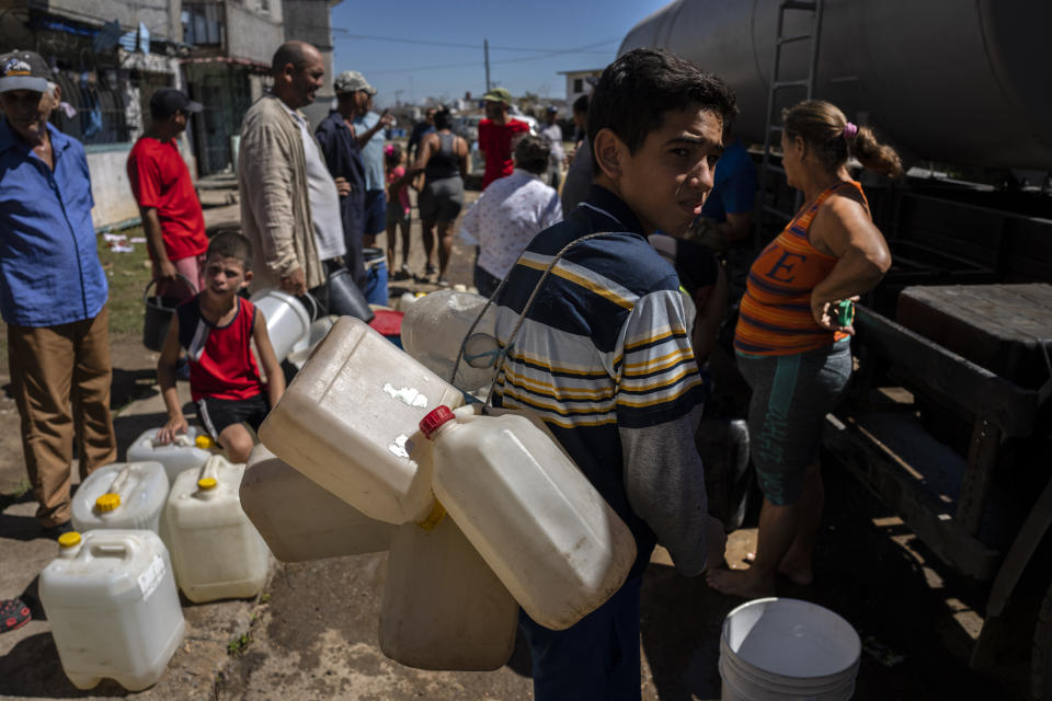 People line up at a tanker truck distributing drinking water amid the aftermath of Hurricane Ian in La Coloma, Pinar del Rio province, Cuba, Wednesday, Oct. 5, 2022. (AP Photo/Ramon Espinosa)