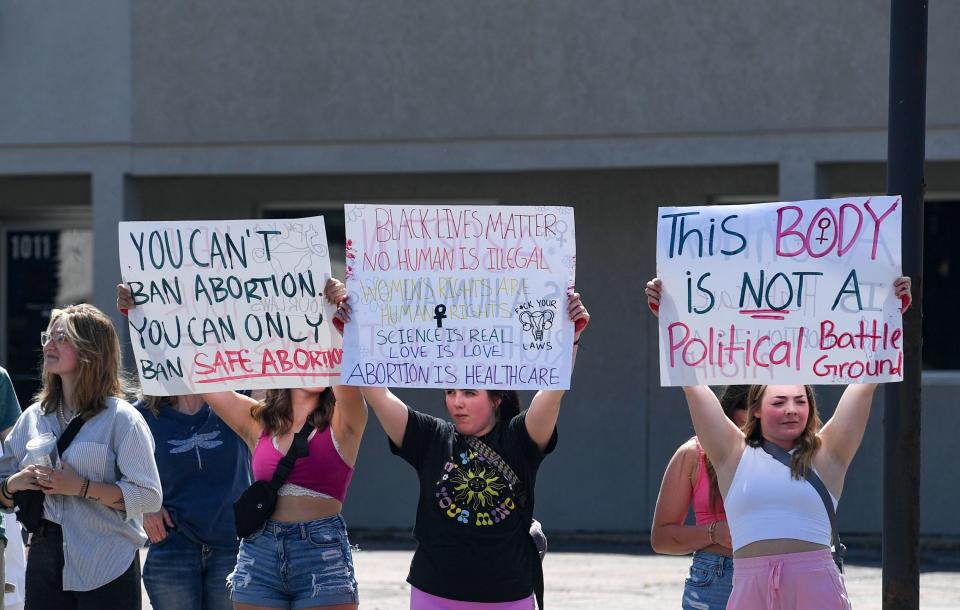 People hold signs protesting the overturning of Roe v. Wade on Minnesota Avenue on Friday, July 1, 2022, in Sioux Falls.