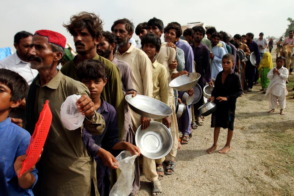 Flood affected people stand in a long line with utensils to get food distributed by Pakistani Army troops in a flood-hit area in Rajanpur, district of Punjab, Pakistan (AP)