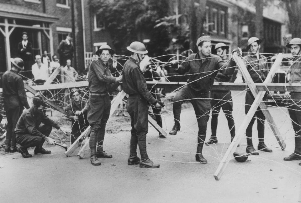 Members of the Rhode Island National Guard string barbed wire defenses on Woonsocket streets in the vicinity of a mill strike riot on Sept. 15, 1934. When the clashes between the strikers and Woonsocket police grew violent, the National Guard was called in.