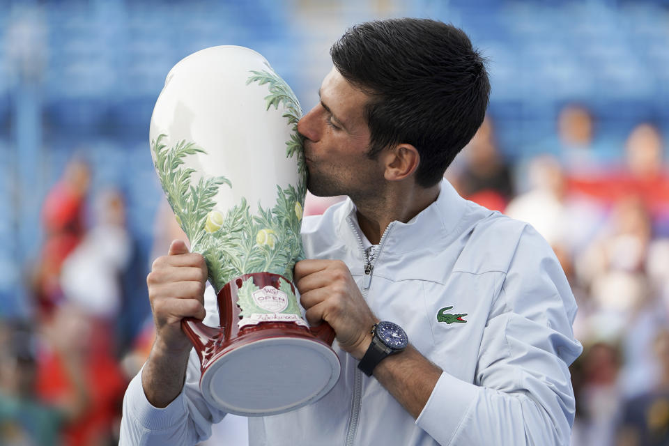 El serbio Novak Djokovic sostiene la Copa Rookwood tras vencer al suizo Roger Federer durante la final del Masters de Cincinnati, el domingo 19 de agosto de 2018, en Mason, Ohio. (AP Foto/John Minchillo)