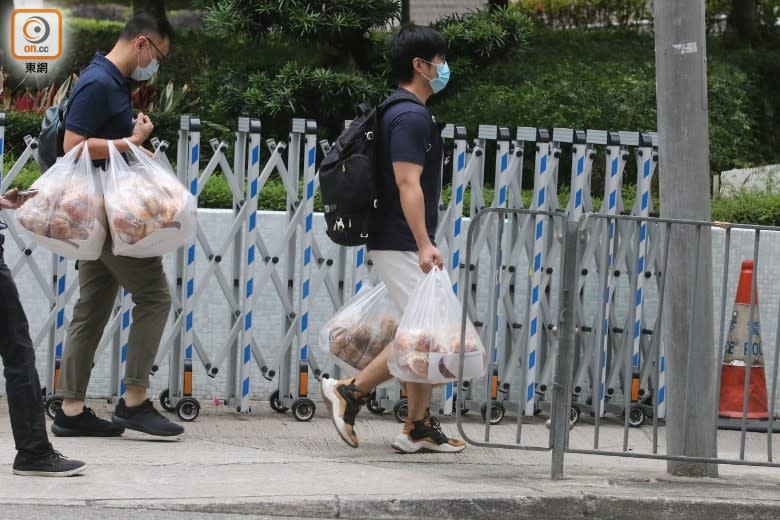 有2名工作人員手持兩大袋麵包到大廈，估計仍有多名居民在內等候。(梁國雄攝)