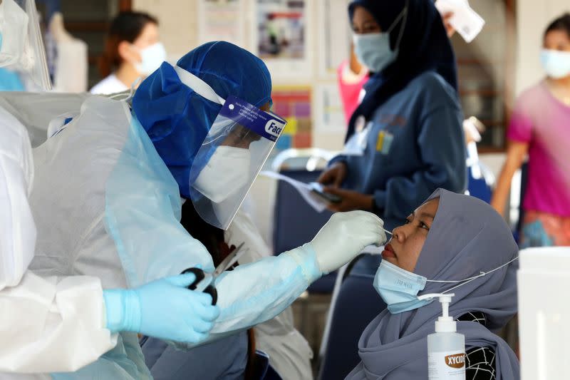 FILE PHOTO: A medical worker collects a swab sample from a Top Glove worker to be tested for the coronavirus disease (COVID-19) outside a hostel under enhanced lockdown in Klang