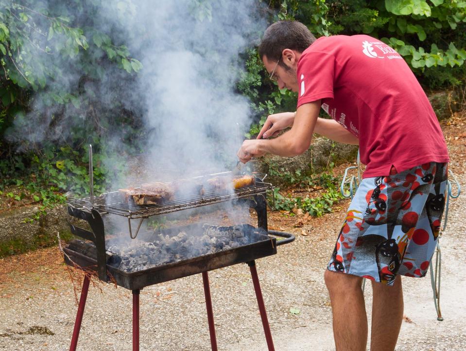 man cooking on a charcoal grill