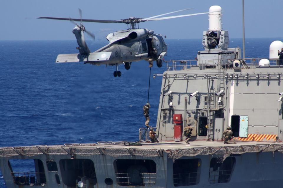 In this photo provided by the Greek Defense Ministry, an helicopter and a warship take part in a military exercise in Eastern Mediterranean sea, on Tuesday, Aug. 25, 2020. Germany's foreign minister appealed to NATO allies Greece and Turkey to deescalate military tensions in the eastern Mediterranean, warning Tuesday that "any spark, however small, could lead to a disaster." (Greek Defense Ministry via AP)