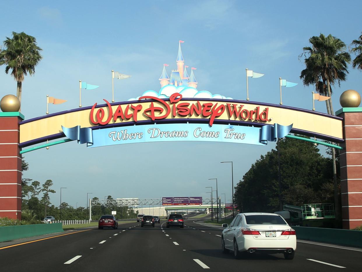 <p>Visitors drive past a sign welcoming them to Walt Disney World on the first day of reopening of the iconic Magic Kingdom theme park in Orlando, Florida, on 11 July 2020</p> ((Photo by GREGG NEWTON/Gregg Newton/AFP via Getty Images))