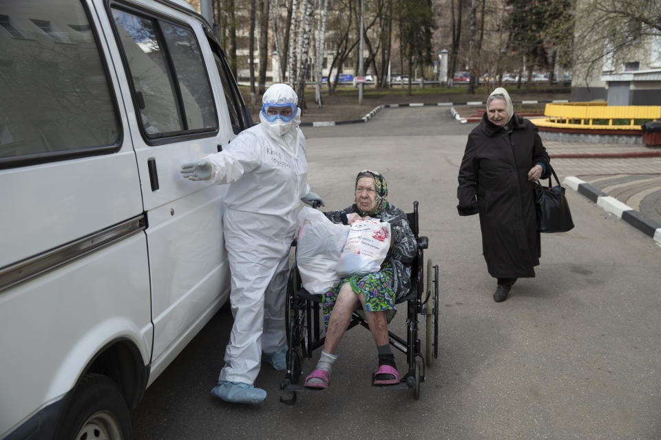 In this photo taken on Tuesday, April 21, 2020, a medical worker helps an elderly woman to get in a car as she was released from the intensive care unit of the hospital of Vinogradov City Clinical Hospital in Moscow, Russia. Reports of Russian medical workers becoming infected with the coronavirus are emerging almost daily as the country copes with a growing number of patients. (AP Photo/Pavel Golovkin)