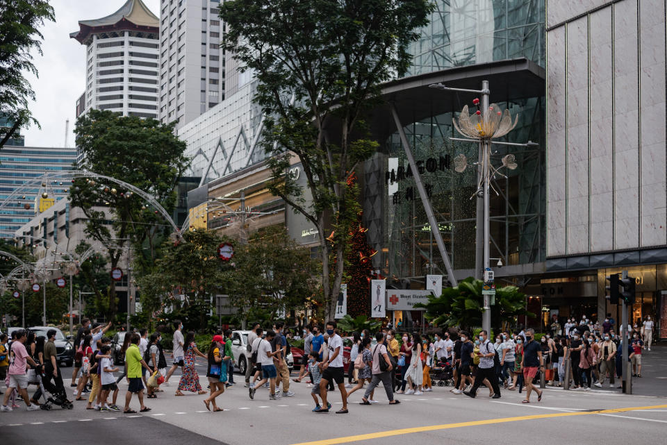 Crowds of people wearing protective face masks walk in Singapore's Orchard Road shopping district on Sunday, 12 December 2021. Singapore authorities reported on 15 December 2021, 2 persons with the Omincron variant of the Covid-19 virus who dined in restaurants along Orchard Road. (Photo by Joseph Nair/NurPhoto via Getty Images)