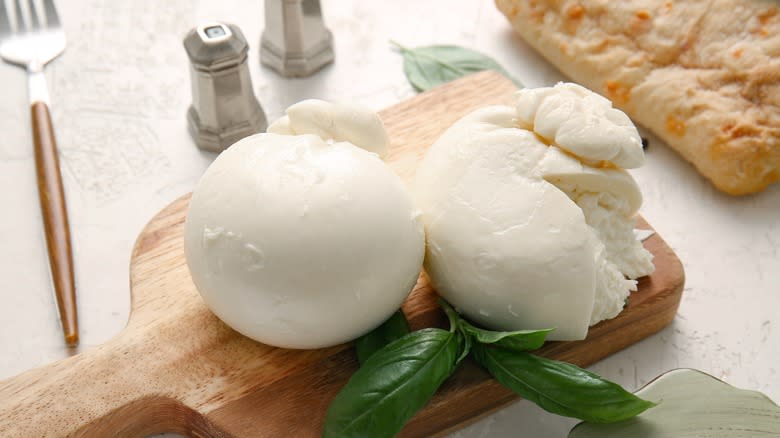 Two burrata balls on wooden board