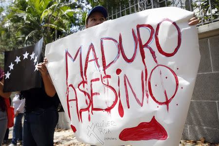 An opposition supporter holds a sign that reads "Maduro murderer" during a gathering to protest the death of an student in Tachira State, in Caracas February 25, 2015. REUTERS/Carlos Garcia Rawlins